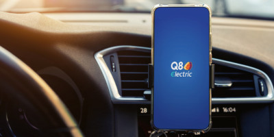 Logo Q8 électrique en grand sur fond bleu sur un smartphone sur un support GPS.  